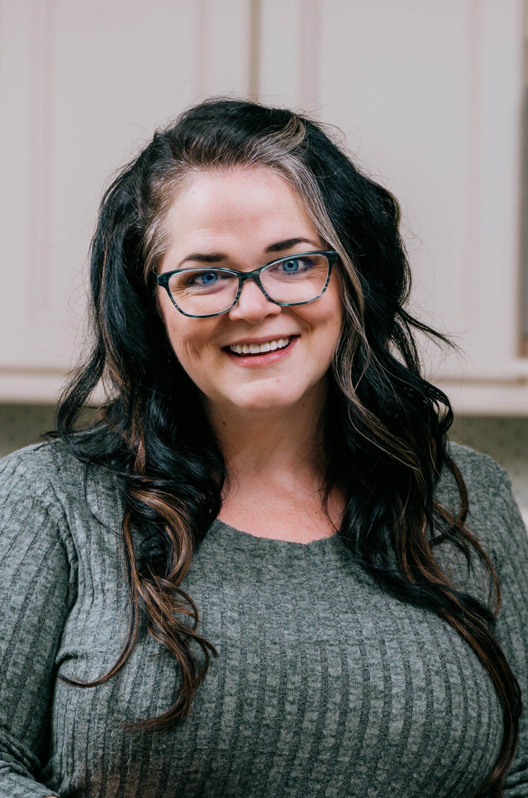 Professional headshot of Jenn Henry, President of SiteWyze, smiling and seated in a home office setting.